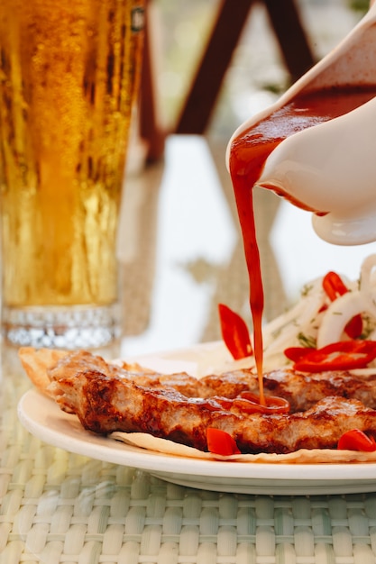 Carne di kebab con ketchup su un piatto bianco versare la salsa nel ristorante