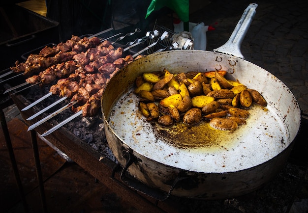 Kebab and roasted potatoes in a large frying pan