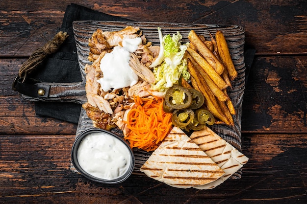 Foto kebab shawarma gyro carne alla griglia con patatine fritte e verdure su una tavola di legno sfondo in legno vista dall'alto