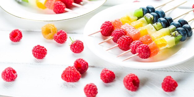 Kebab with raspberries kiwi orange and other fruits on the plate