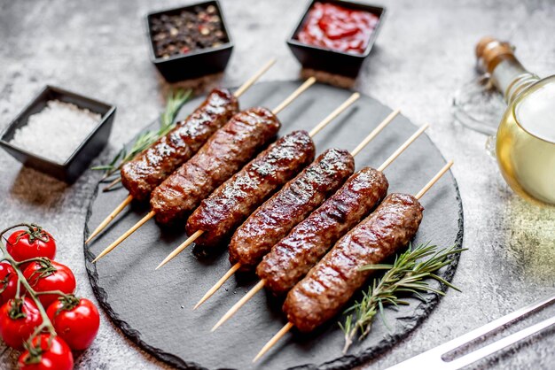 Photo kebabs on a black plate with a red sauce on it