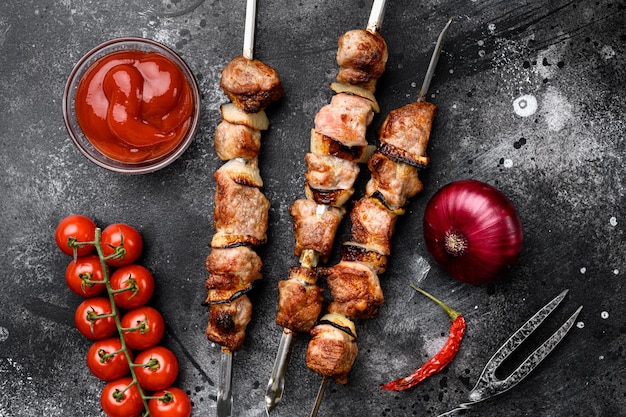Шашлык на гриле, шашлык из мяса, набор для шашлыка, на черном фоне темного каменного стола, плоский вид сверху