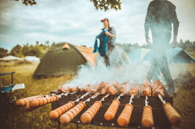 Kebabs on skewers people and tentsin the background