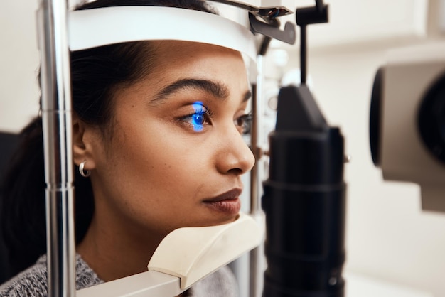 Photo keep as still as possible shot of a young woman getting her eyes examined with a slit lamp