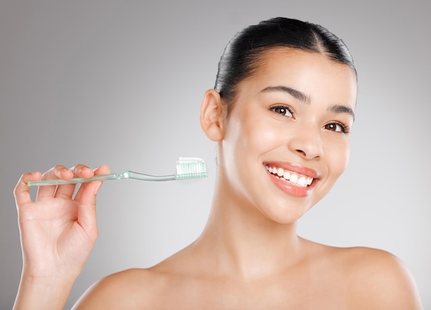 Keep brushing keep smiling Studio shot of an attractive young woman brushing her teeth against a grey background