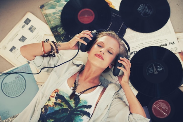 Keep calm and let the music play on A young woman listening to music while lying on her back and surrounded by records