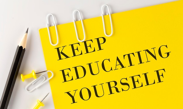 Keep Educating Yourself word on the yellow paper with office tools on white background