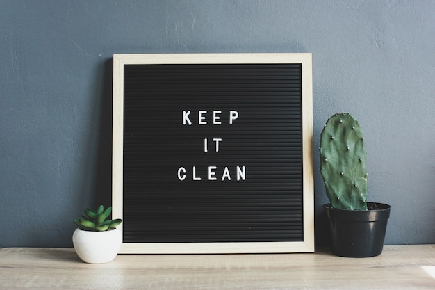 KEEP IT CLEAN citaat op bord met cactus en sappig op houten tafel