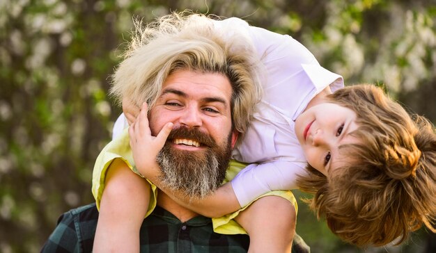 Photo keep smiling. enjoy bloom and nature together. happy family day. spring is coming. just have fun. love concept. cheerful father playing with his child in park. handsome dad with his little cute son.