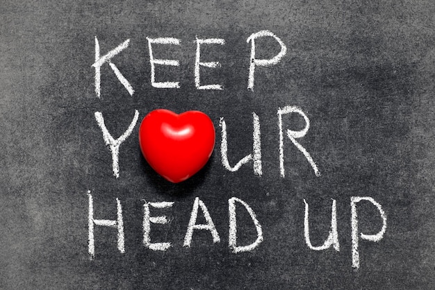 Keep your head up phrase handwritten on blackboard with heart symbol instead of O