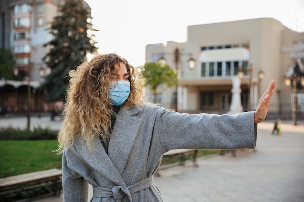 Foto mantieni la distanza sociale. donna nella maschera facciale di protezione da virus che mostra il gesto stop infezione. coronavirus covid-19 pandemia e concetto di assistenza sanitaria.