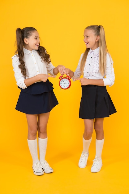 Keep your students safe and on time happy little girls holding retro clock during school time on yellow background small child holding alarm clock time to learn school clock and time solution