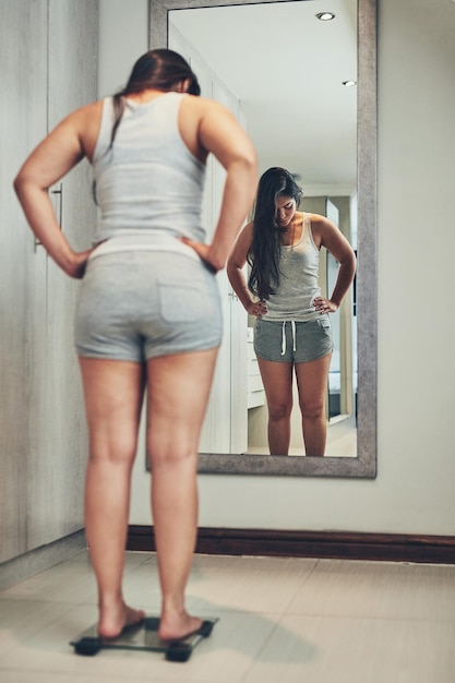사진 그녀의 체중을 면밀히 관찰 집에서 체중계에 자신의 무게를 재는 젊은 여성의 샷