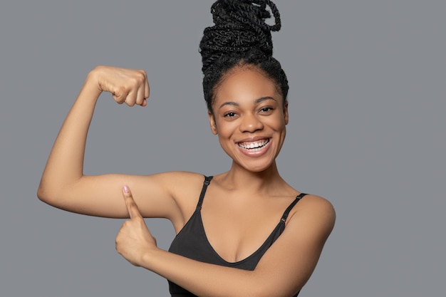 Keeping fit. Cute mulatta in black showing her muscles