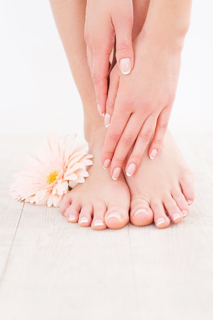 Photo keeping her feet clean and smooth. close-up of woman touching her feet while standing on hardwood floor