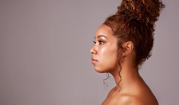 Keeping her hair on the curly side of things Studio shot of a beautiful young woman posing against a gray background