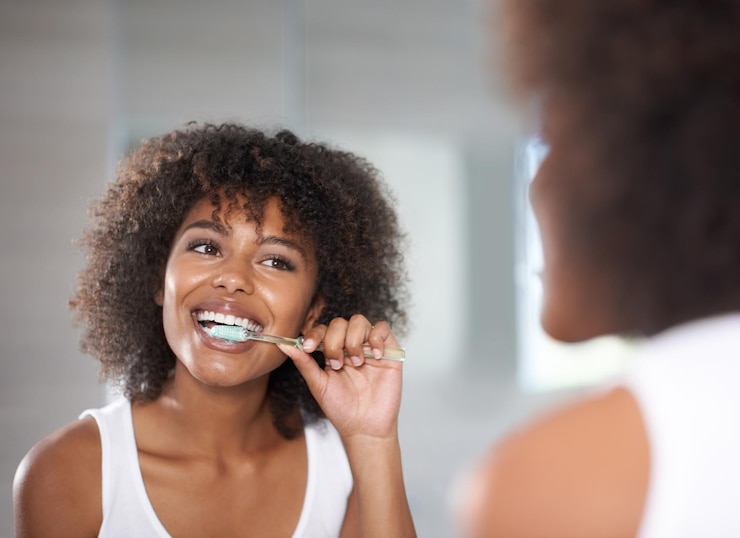 Photo keeping her smile shot of a a young woman brushing her teeth