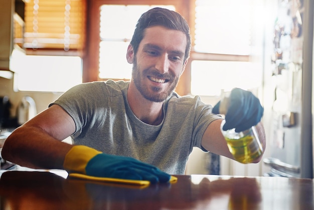 Keeping his home completely spotless Cropped shot of a young man cleaning a kitchen surface at home