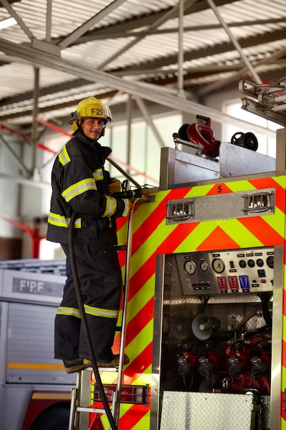 Photo keeping you safe from fire a young male firefighter on the ladder at the back of a firetruck