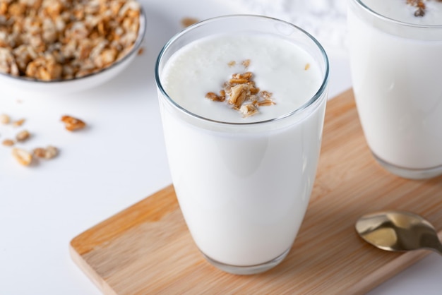 Kefir karnemelk of yoghurt met muesli Yoghurt in glas op witte houten achtergrond Probiotische koude