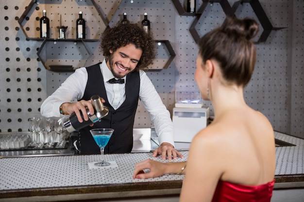 Kelner gietende cocktail in het glas van de vrouw bij barteller