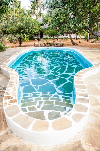 Kenia. piscina di lusso in giardino africano con sedie tipiche locali in legno sullo sfondo