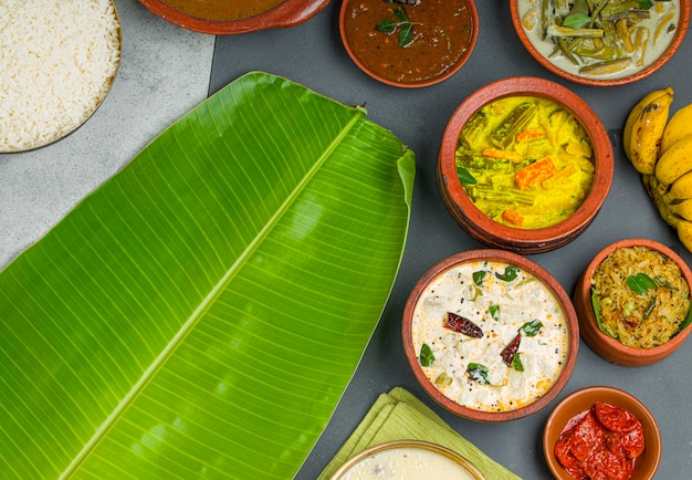 Kerala traditional feast side dishes arranged  in a two colour background with banana leaf for serving food