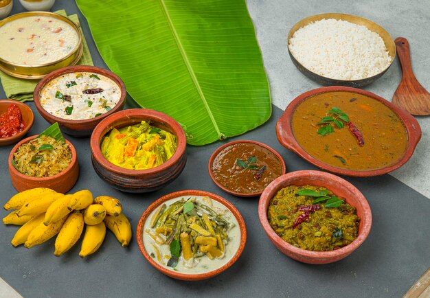 Kerala traditionele feestbijgerechten en gekookte rijst gerangschikt op een tweekleurige achtergrond met vers groen bananenblad ernaast