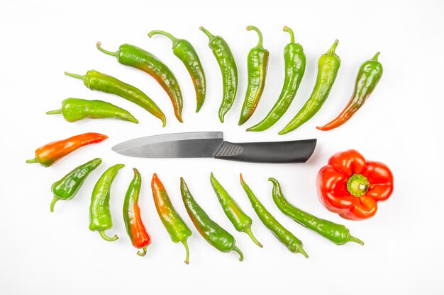 Keramisch mes en groene hete pepers op een witte achtergrond. groenten koken voor voedsel