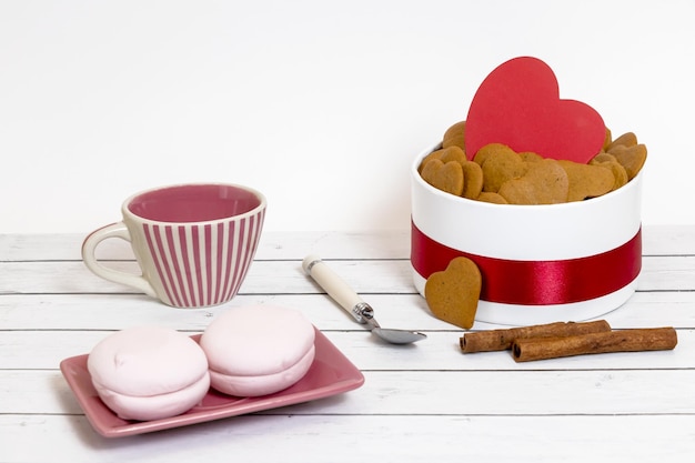 Keramische beker marshmallows en hartvormige koekjes op een lichte houten ondergrond