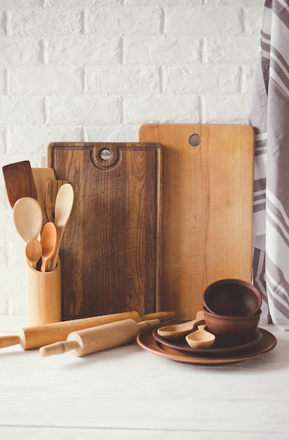 Keramische borden, houten of bamboe bestek, snijplanken en handdoek in het interieur van de keuken.