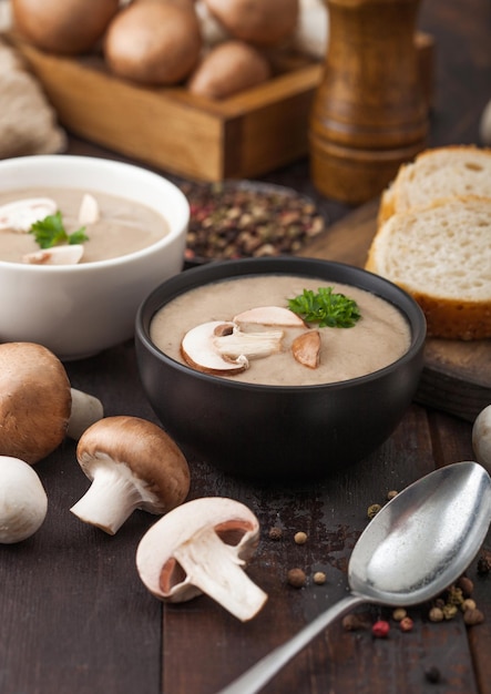 Keramische komplaten van romige kastanjechampignon-champignonsoep met lepelpeper en keukendoek op donkere houten plank