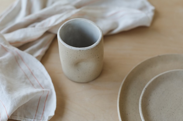 Foto keramische kop en borden op een houten tafelblad, minimalistische set handgemaakt keramisch servies en p...