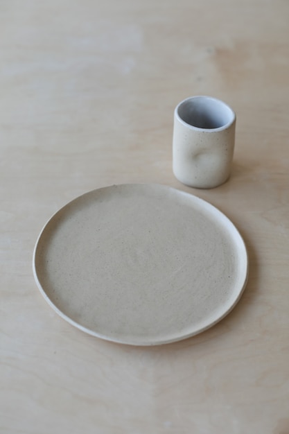 Keramische kop en borden op een houten tafelblad, minimalistische set handgemaakt keramisch servies en p...