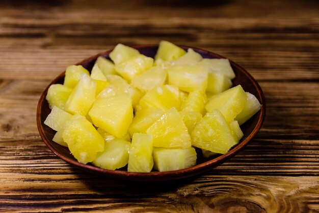 Keramische plaat met gehakte ananas in blik op rustieke houten tafel