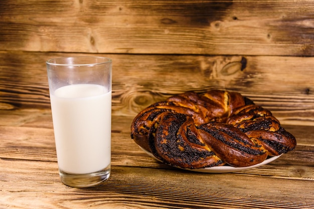 Keramische plaat met maanzaadbroodje en een glas melk op houten tafel