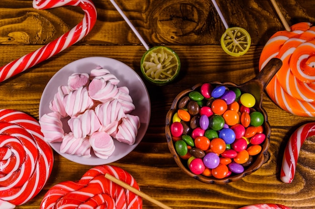 Keramische plaat met marshmallow, snoepgoed en lollies op rustieke houten tafel. Bovenaanzicht