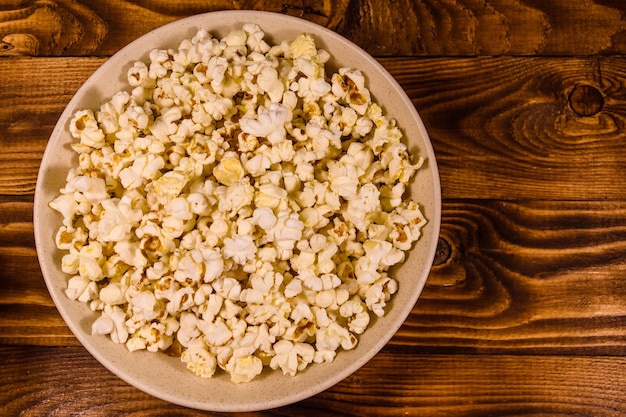 Keramische plaat met popcorn op houten tafel Bovenaanzicht