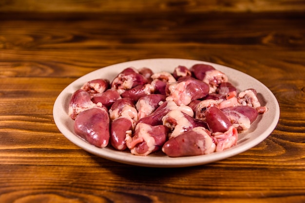 Keramische plaat met rauwe kippenharten op houten tafel