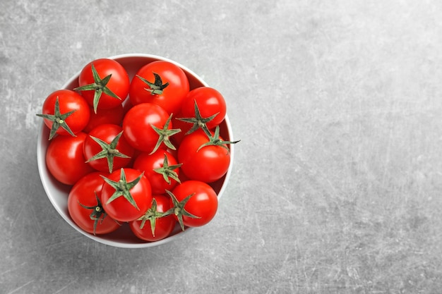Keramische schaal met rijpe kersen tomaten op een lichte achtergrond