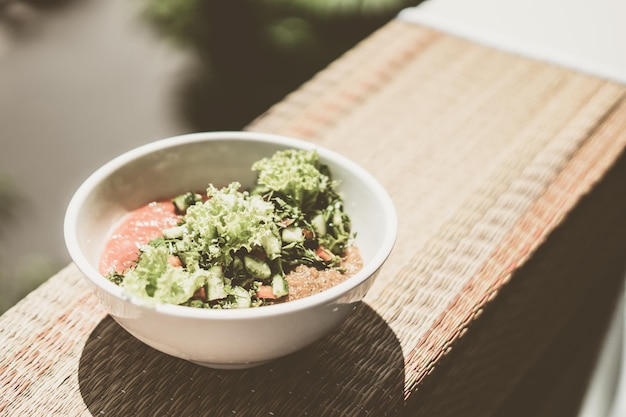 Keramische witte lichte kom met mix groene sla bladeren spinazie blad salade ingrediënten verse groenten gepureerde rode tomaat serveerschaal gezonde veganistische voeding keuken close-up weergave van bovenaf