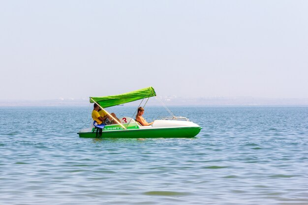 Kerch, Rusland - 13 augustus 2019: drie jonge badmeesters op een witte en groene catamaran drijven langzaam op het zeewater op een zomerdag