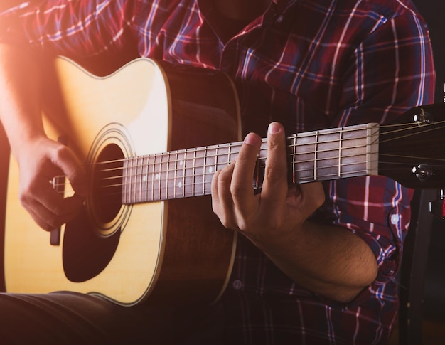 Kerel die een akoestische gitaar speelt in een opnamestudio.