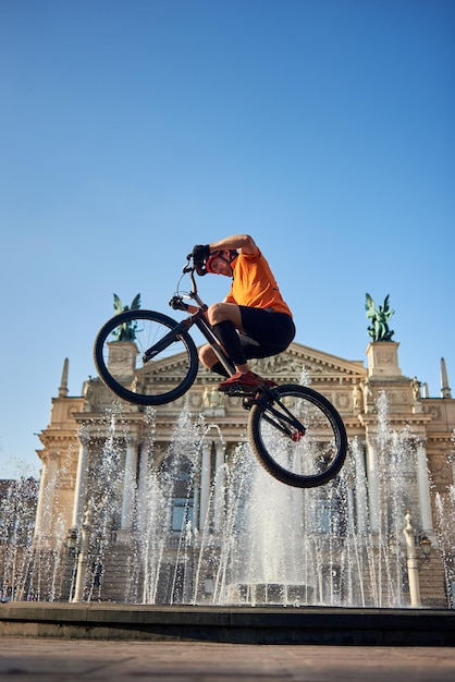 Kerel die fietsstuur op architectuurachtergrond houdt