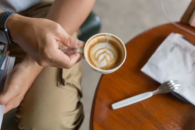 Kerel die ladingsbroek draagt en een koffie in koffiewinkel drinkt