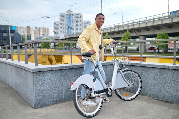 Kerel die met fiets staat en naar de camera kijkt