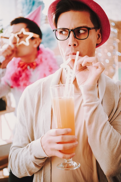 Kerel in glazen met een cocktail bij een vrolijk feestje.