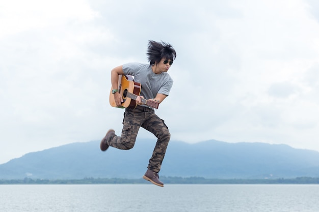 Kerel met gitaar die zich op de dam bevindt