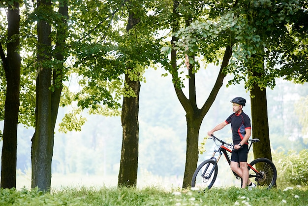 Kerel professionele fietser die zich dichtbij fiets in mooi zonnig groen park bevinden