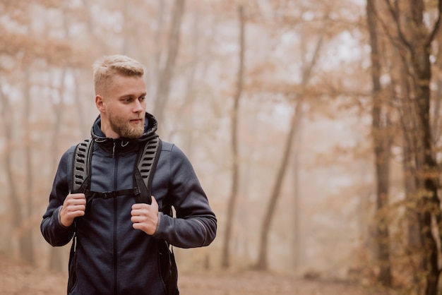 Kereltoerist loopt in een mistig de herfstbos